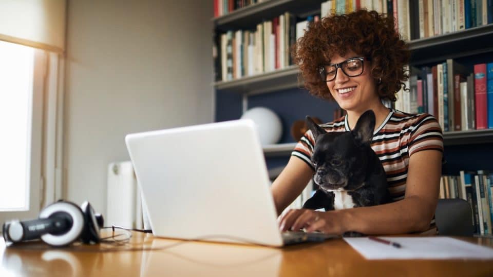 Woman working on laptop with dog
