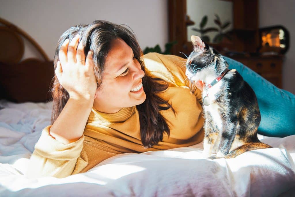 Shot of a young woman lying on her bed and bonding with her cat