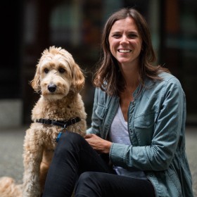 smiling woman petting a small white and brown dog