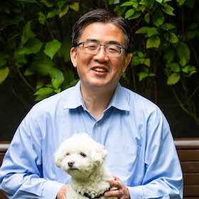 smiling man holding a small white dog