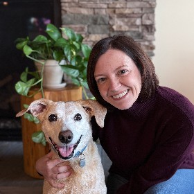 smiling woman holding a happy blonde dog