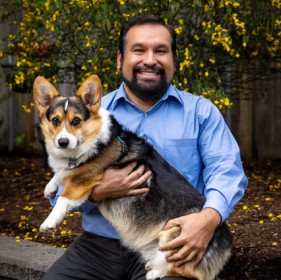 smiling man sitting with a black and brown dog