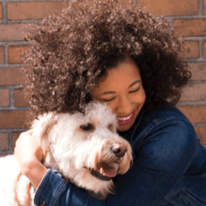 Smiling woman hugging a white shaggy dog