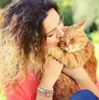 Woman kissing an orange tabby cat
